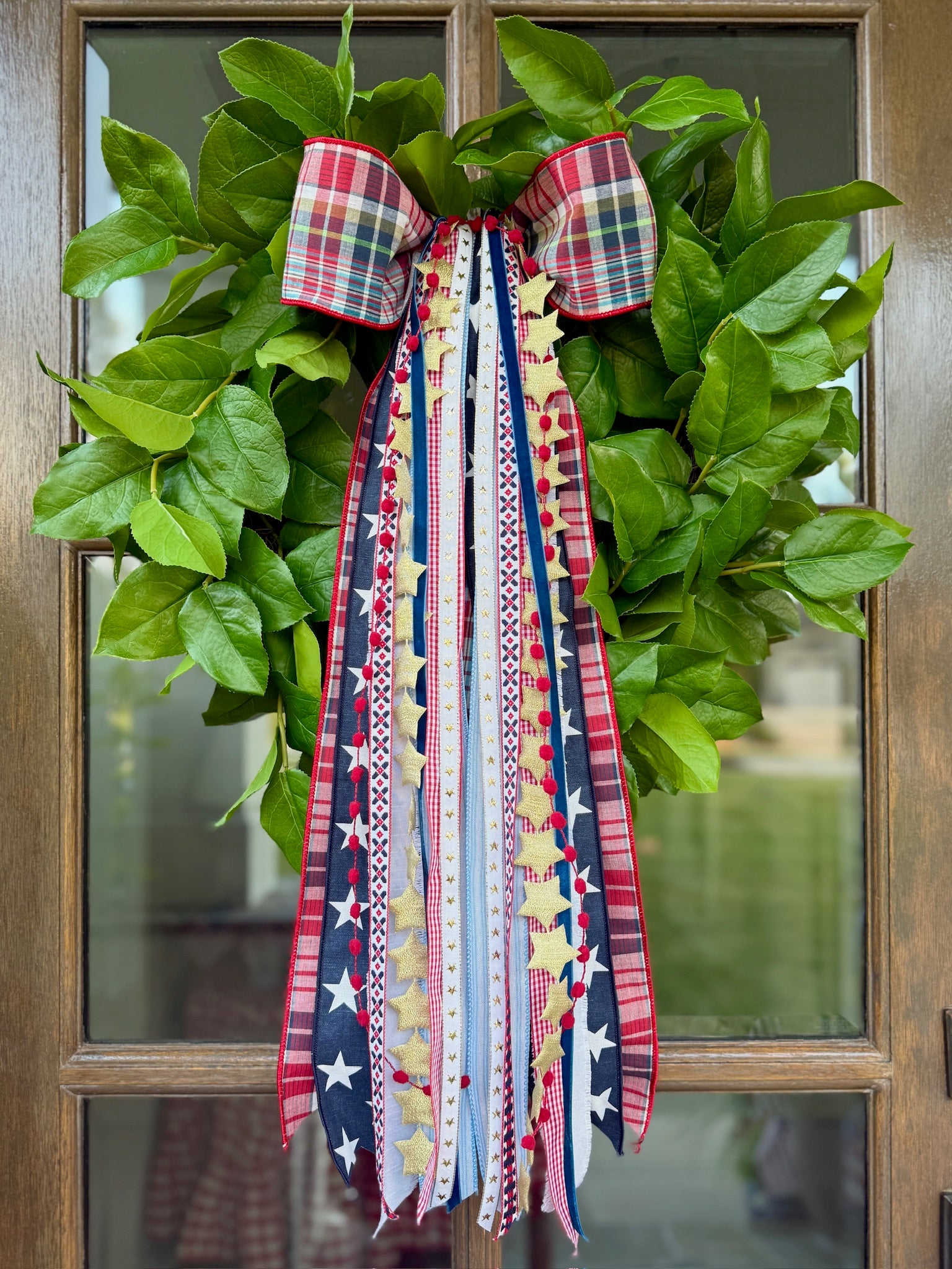 Patriotic plaid bow and ribbon wreath on green leaves