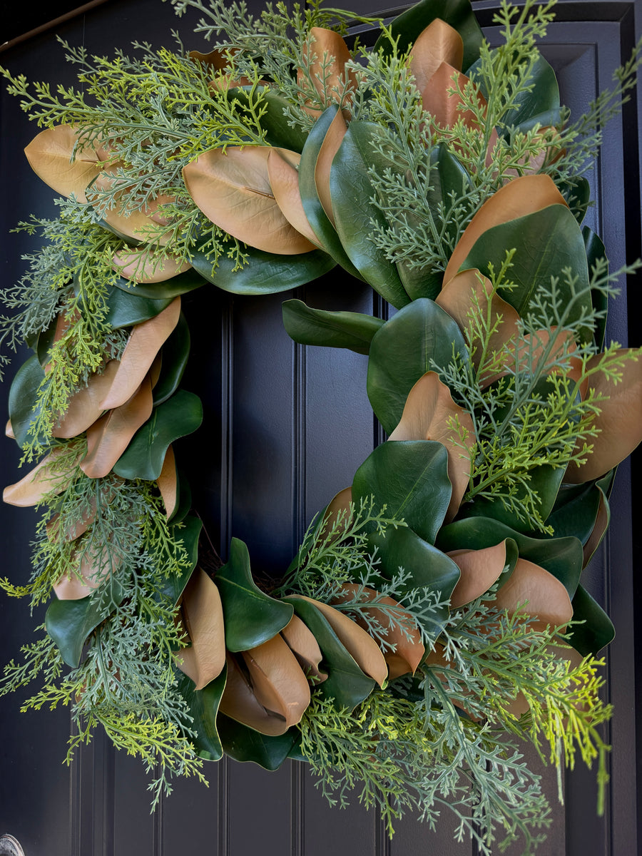 Front view of Turnberry Magnolia Evergreen Wreath showcasing magnolia leaves and evergreen foliage on a black paneled door