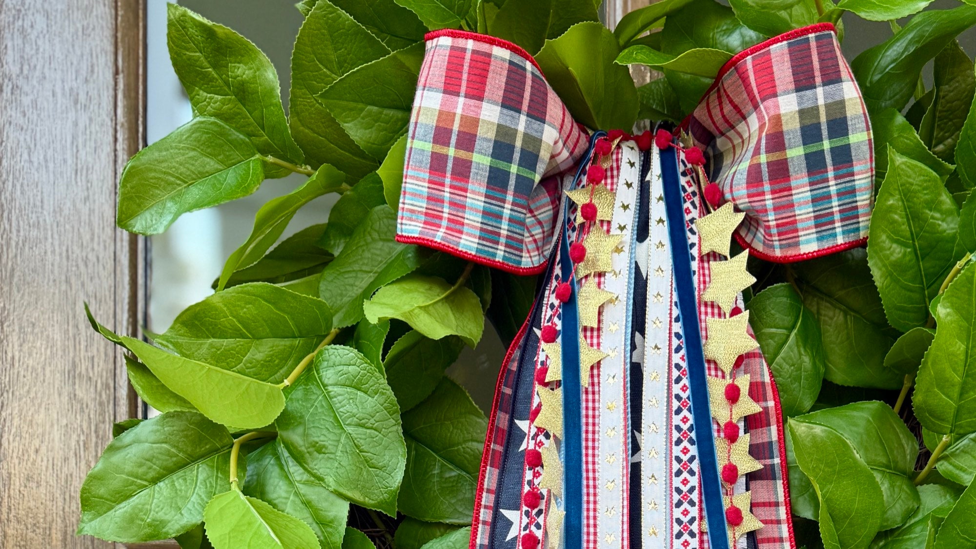 Patriotic plaid bow and ribbon wreath on green leaves