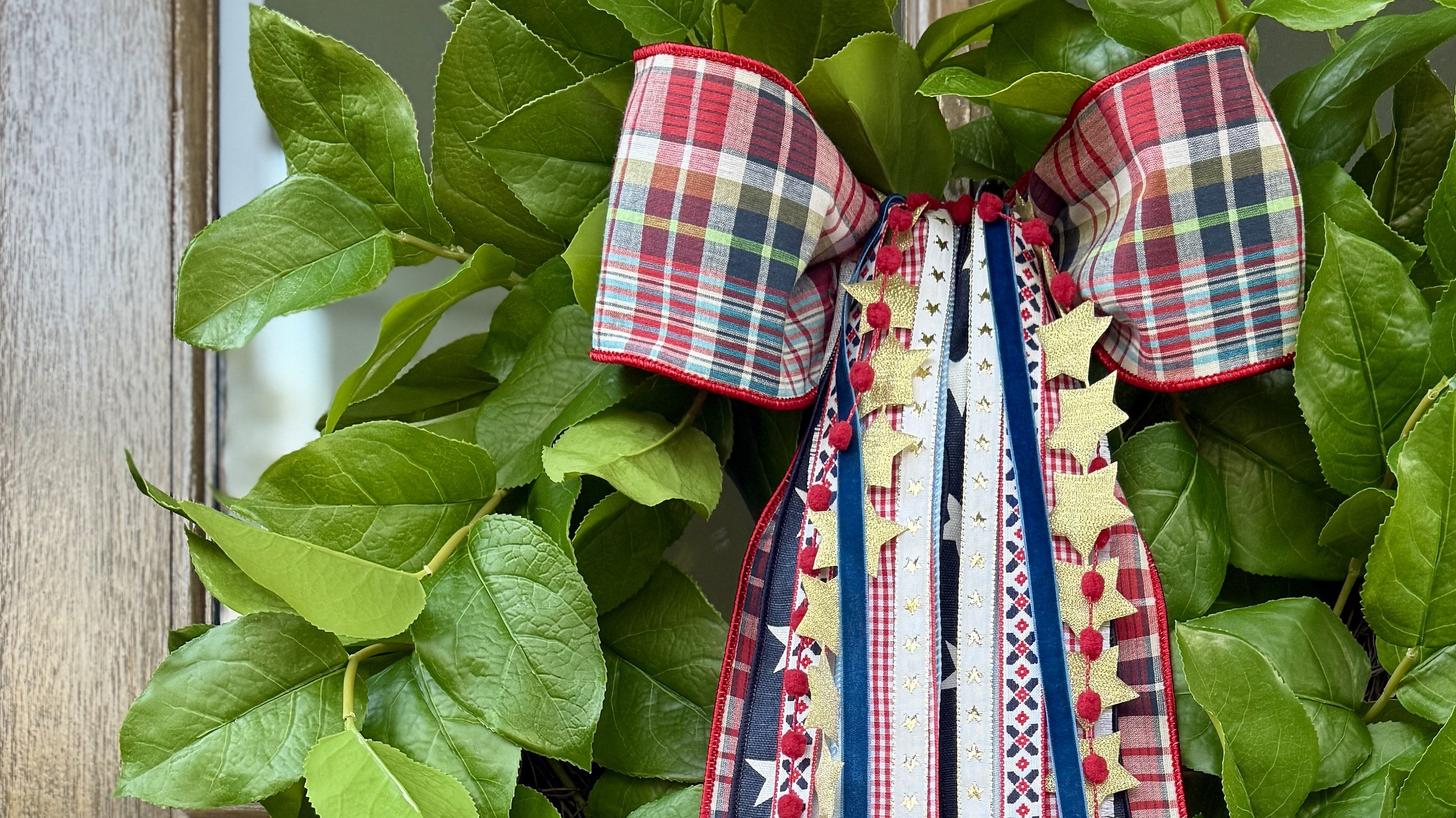 Patriotic plaid bow and ribbon wreath on green leaves