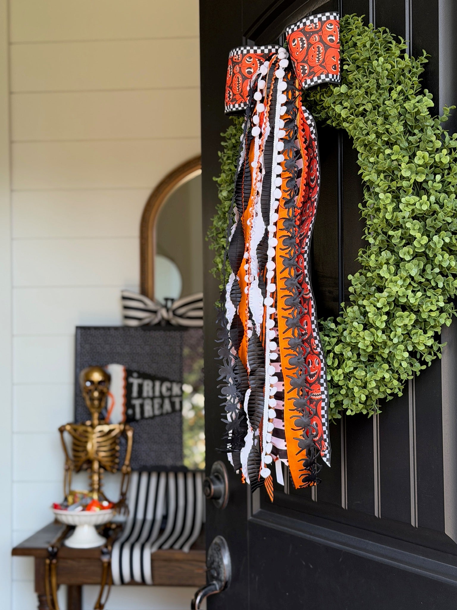 Orange and black Halloween ribbons on a green front-door wreath