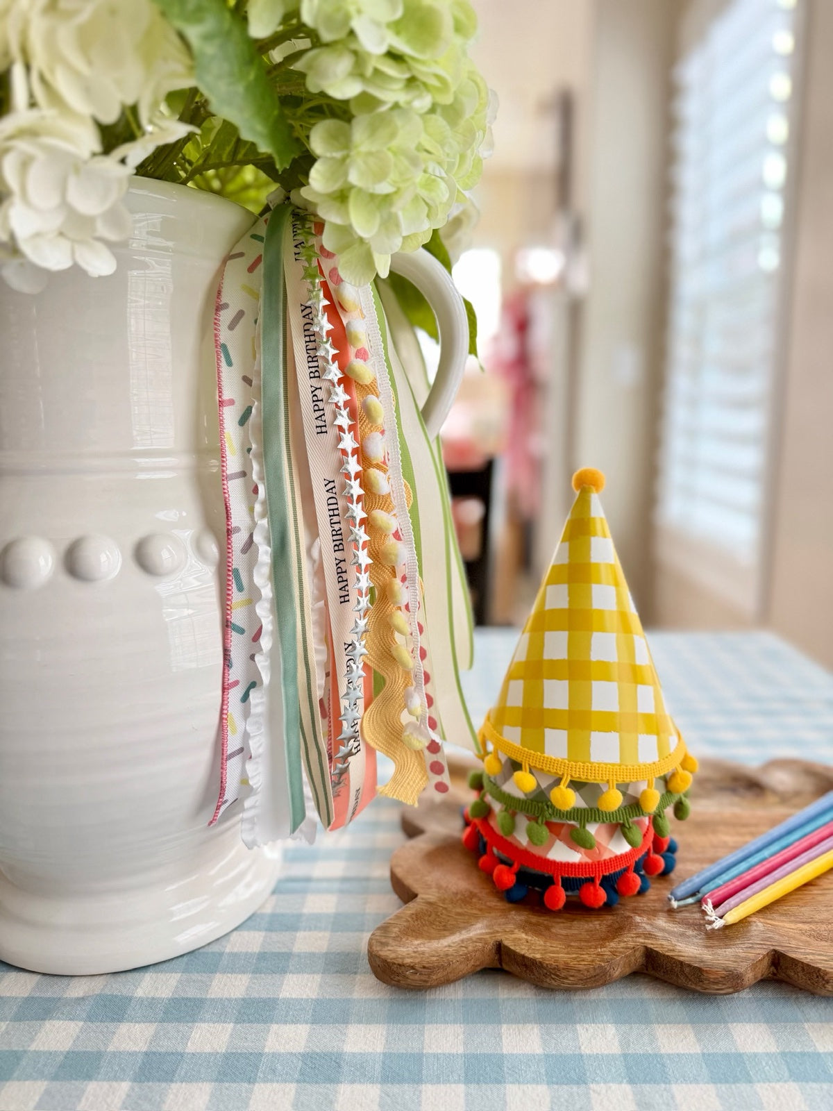 Birthday ribbons styled with flowers and a colorful party hat