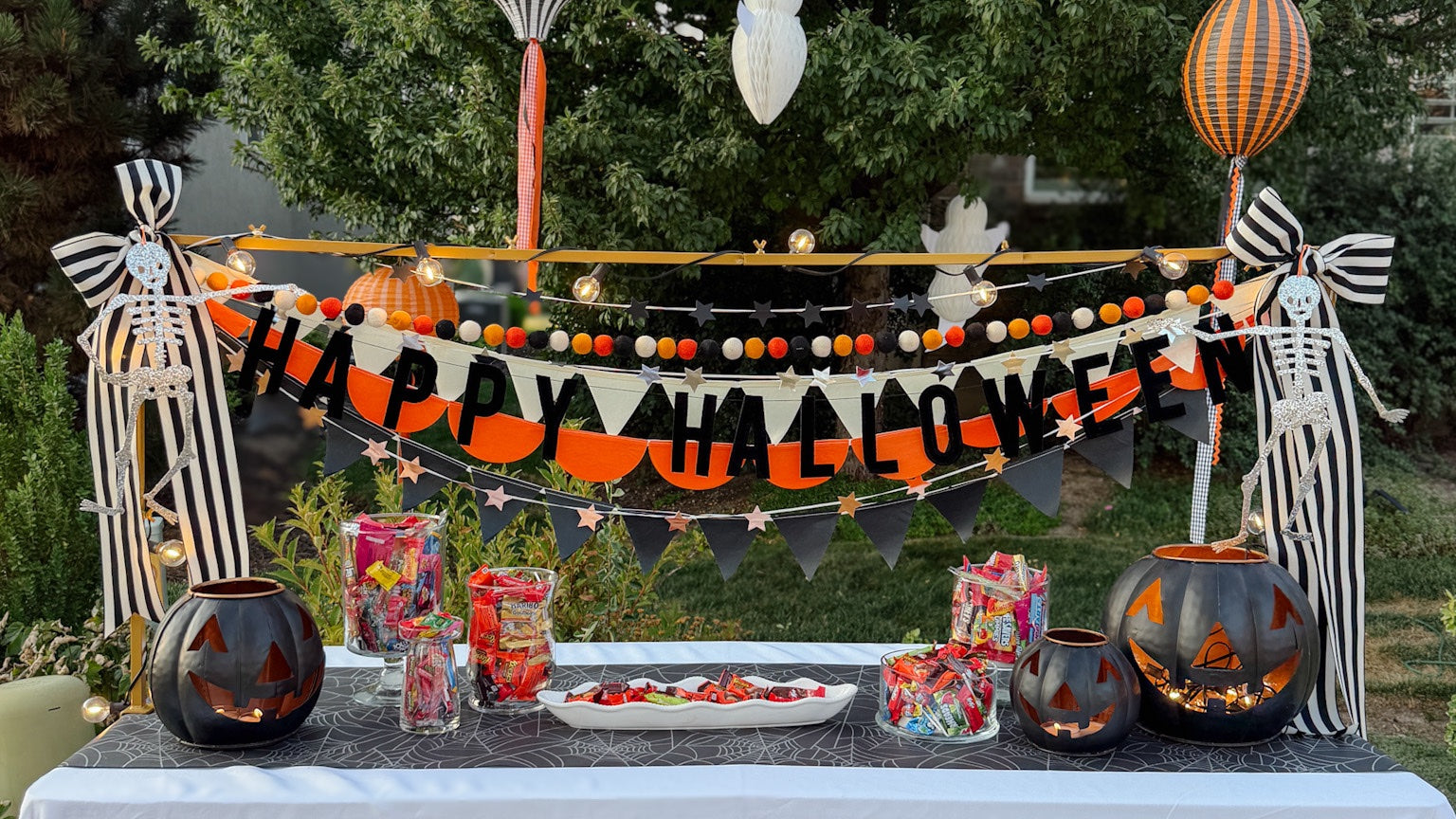 Halloween party table styled with black, orange, and white decorations