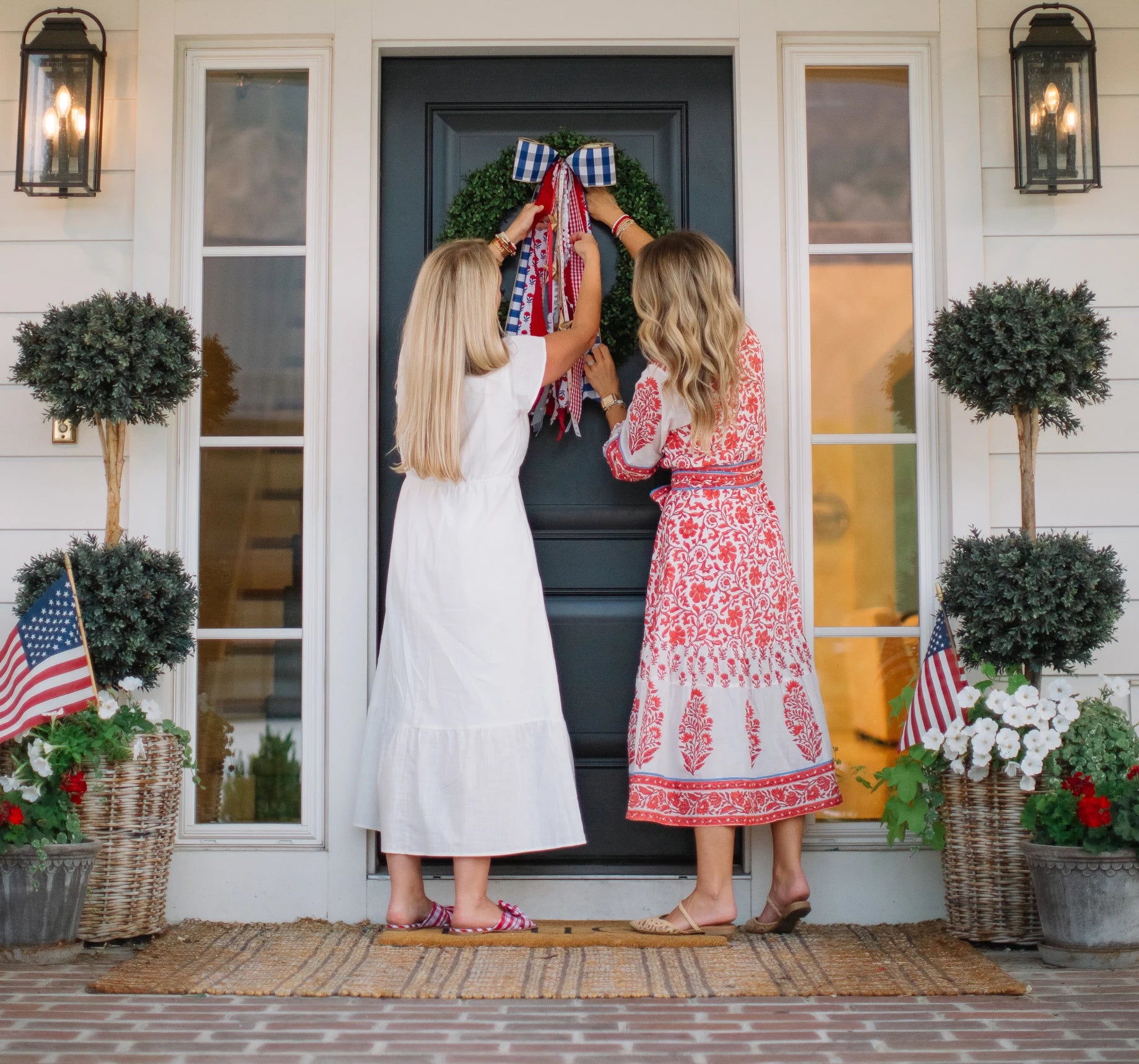 House of Turnberry founders styling a red, white, and blue ribbon set on a front-door wreath.